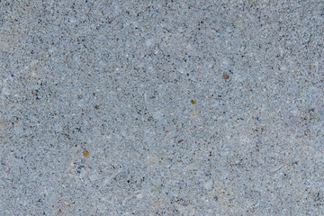 The surface of the concrete road has small grains of sand and black stains.