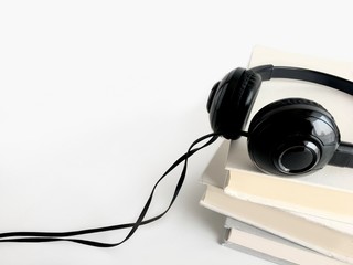 Black headphones laying on top o books. Copy space background of audio book and Podcast concept.