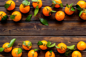 Tangerines with leaves frame on dark wooden background top-down copy space