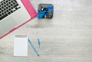 Office workplace top view with open laptop, blank notebook, pen and pencil box. Overhead shot with copy space on grey wooden table surface background