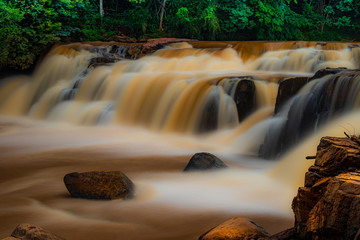 cachoeira com águas de tonalidade marrom devido a fortes chuvas criando sensação de areia