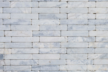 White natural stone marble brick masonry wall outside of the building. Rough surface texture exterior of stone wall. Design and decoration concept with copy space for text.