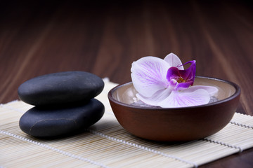 Massage stones with orchid stock images. Spa and wellness setting stock images. Pile of black stones. Black stones on a nature background. Spa-concept with zen stones and orchid flower stock images