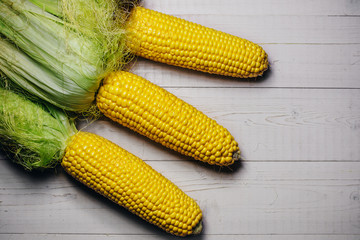 Three ears of corn on a white wooden table - rural view