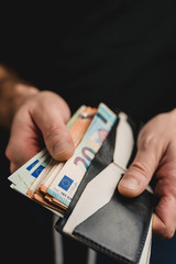 Cash payment - A man takes out euro bills from his wallet