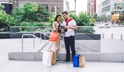 Curious tender loving couple viewing photos by sub on urban street