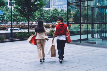 Delighted multiethnic couple promenading after shopping