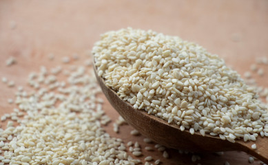 Full spoon of white sesame seed on a wooden board. Wooden spoon on a white background. Home.