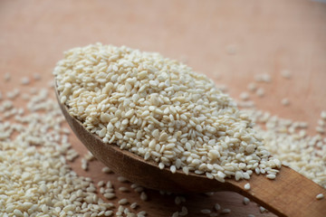 Full spoon of white sesame seed on a wooden board. Wooden spoon on a white background. Home.