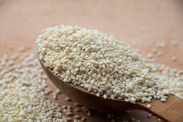 Full spoon of white sesame seed on a wooden board. Wooden spoon on a white background. Home.