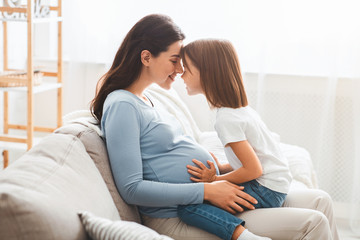 Obraz premium Young pregnant woman bonding with her little daughter