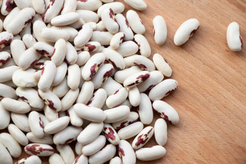 White bean with red dots. Many. On a white and wooden background. Protein.