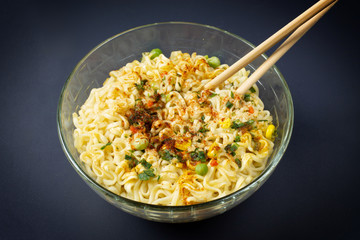 Instant noodles with spices in a plate on dark background