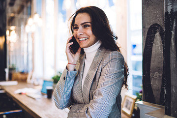 Cheerful woman speaking on cellphone in cafe