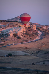 Cappadocia, Turkey, Europe: a hot air balloon floating at dawn and view of the valley around Cavusin, town of the historical region in Central Anatolia rich of exceptional natural wonders