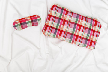 Pillow and Eye mask for sleeping on white cotton bedsheet. Healthy sleep. Top  view. Flat lay.