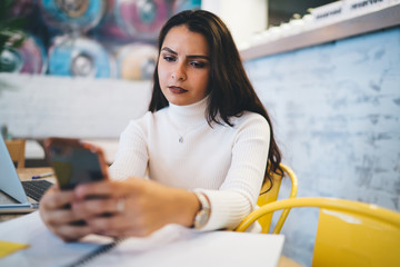 Calm female browsing phone in cafeteria