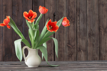 tulips in vase on dark wooden background