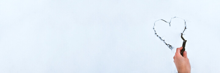 Heart drawn by stick on white snow . Beautiful winter background for Valentines Day or Christmas with copyspace. Stock photo.