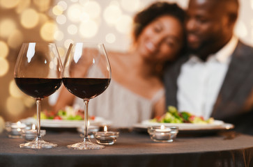 Selective focus on two glasses of wine over cuddling couple