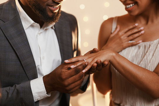 Black man putting ring on his woman finger