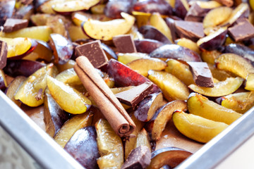 Fresh plum fruit cut into slices, slices with cinnamon sticks, chocolate, cloves. Preparation of ingredients and fruits for making delicious jam.