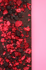 Dark chocolate with dried red berries on bright pink background