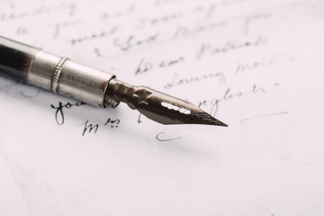 Fototapeta premium Fountain pen on an ancient handwritten letter. Old story. Retro style.
