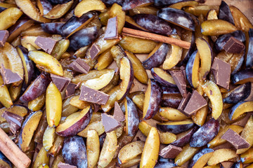 Fresh plum fruit cut into slices, slices with cinnamon sticks, chocolate, cloves. Preparation of ingredients and fruits for making delicious jam.