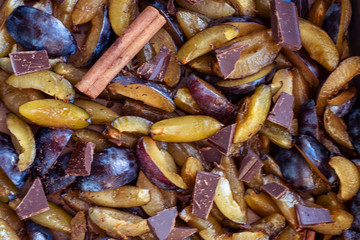 Fresh plum fruit cut into slices, slices with cinnamon sticks, chocolate, cloves. Preparation of ingredients and fruits for making delicious jam.