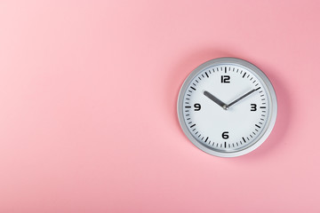 White wall clock with a yellow used hanging on the wall. Minimalist image of a wall clock on a pink background with copy space