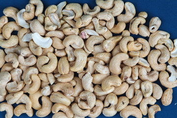 Cashew seeds texture top view on blue color background, space for text, organic healthy food concept