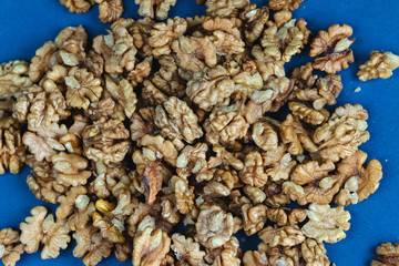 Walnut seeds texture top view on blue color background, space for text, organic healthy food concept