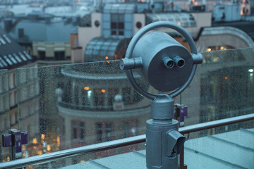 Tourist binoculars with raindrops on an observation deck in the center of the old city