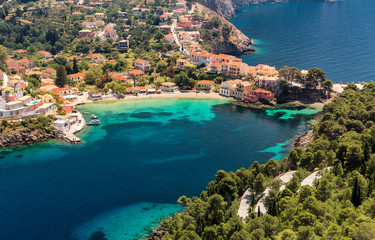 Obraz premium Amazing coastline with colorful houses under sunlight. Wonderful summer seascape with perfect blue sky of Ionian Sea. Assos village. Kefalonia. Greece. aerial shot.