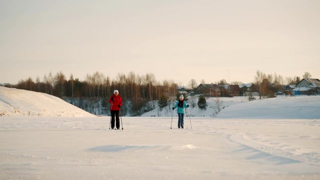 Woman with her daughter skiing on a frozen lake on a sunny day. Winter skiing trip of daughter and mother.