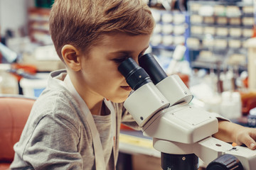 Small boy using microscope in engineering lab.