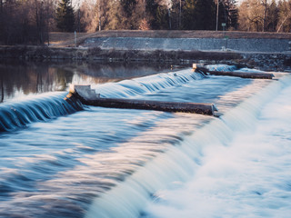 Water flowing over a weir during sunset in the winter, Augsburg, Germany