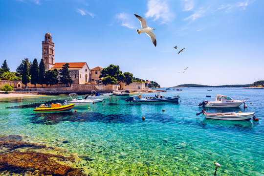 View at amazing archipelago with fishing boats in front of town Hvar, Croatia. Harbor of old Adriatic island town Hvar with seagull's flying over the city. Amazing Hvar city on Hvar island, Croatia.