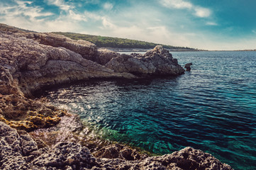 Aerial view of  turquoise calm sea  against rocks. Wonderful beauty wild beach with stony rocky shore, shallow sea water. Beautiful scenery and sunny day on Kefalonia Island, Greece. Natural texture