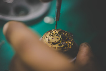 Close up image of a watch maker fixing a broken watch with precision tools