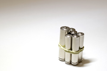 Several cylindrical batteries are tied in a bundle with a yellow stationery elastic band. Macro. Selective focus.