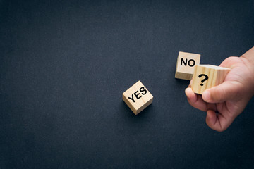 Fototapeta na wymiar Wooden alphabet cube with words YES or NO closeup and children hands on black background. Selective focus and education concept