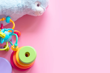 Flat lay border of different baby toys on a pink background with copy space