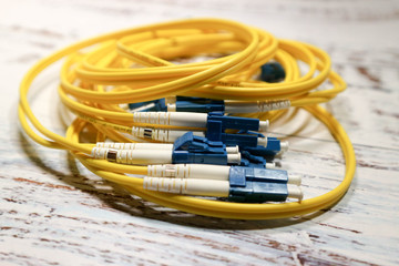 closeup of yellow optical fiber network cables isolated on wooden table background