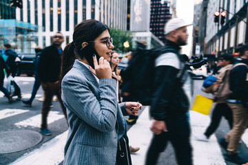 Side view of successful female entrepreneur formally dressed doing crosswalk on way to office enterprise using roaming internet for online communication, positive businesswoman calling to partner