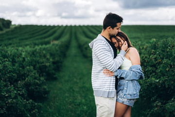 Young loving couple gently hugging on the background of green currant plantations. Love Story