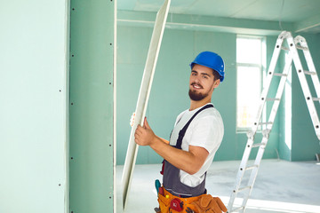 Worker builder installs plasterboard drywall at a construction