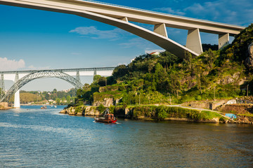 View of a vintage traditional boat sailing on the Douro River and some of the bridges that cross over it