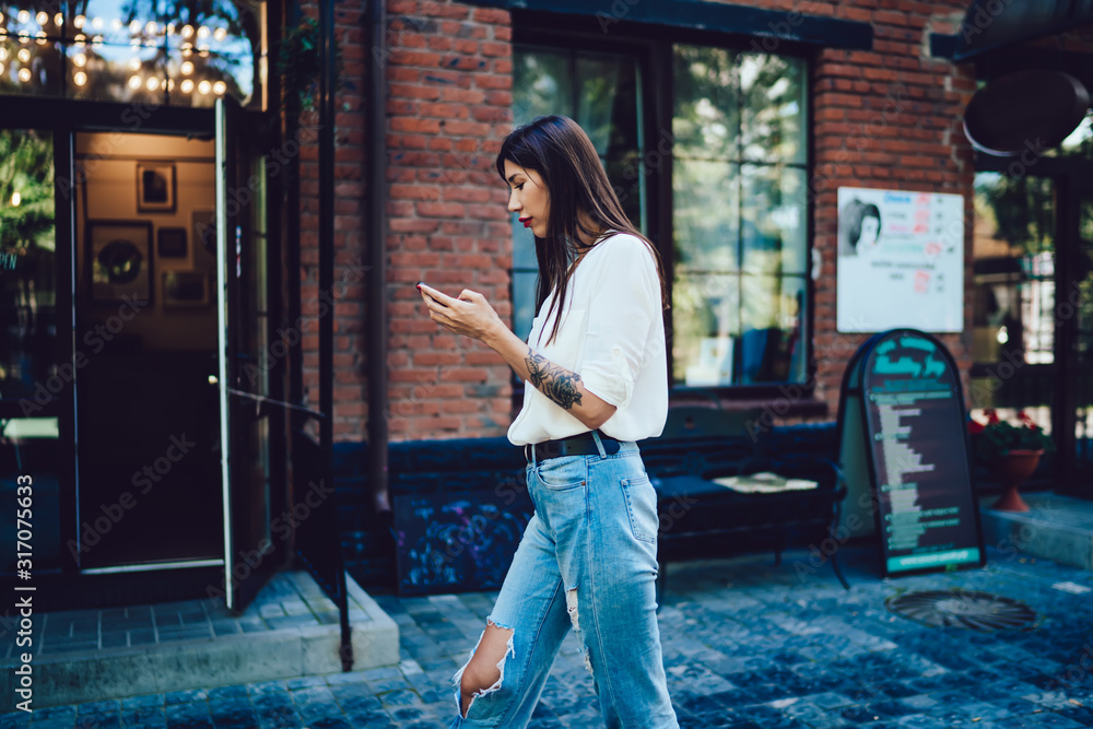 Poster side view of millennial female blogger installing medial application to smartphone device for editin